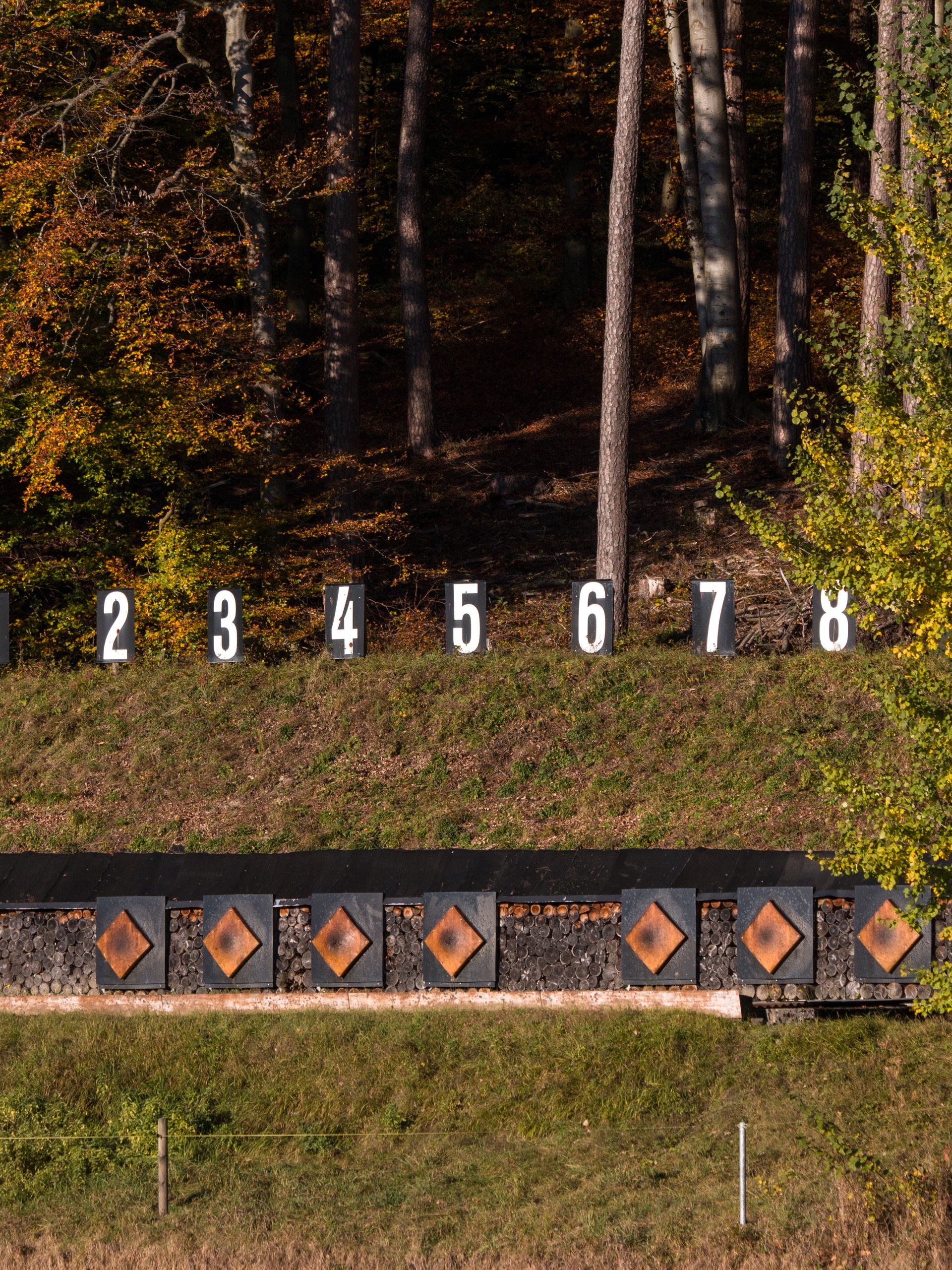 There is an outdoor shooting range with targets sitting on the ground between an opening in the thick trees and foliage.